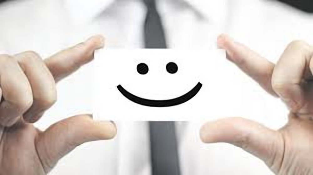 Mains tenant une carte sur laquelle est dessiné un sourire